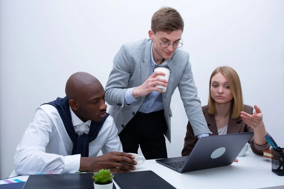 Hands using smartphone beside laptop with stock charts, showcasing digital trading.